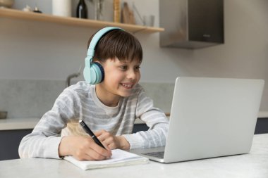 Neşeli gülümseyen genç çocuk evde uzaktan çalışıyor..