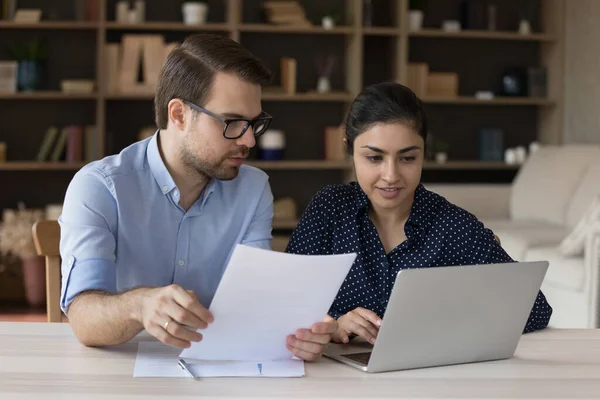 Two diverse coworker employees sharing laptop, discussing paper report — Stock Photo, Image