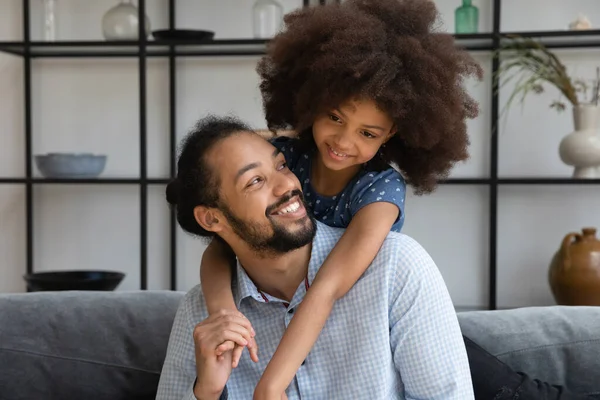 Vrolijk klein Afrikaans Amerikaans meisje knuffelen liefdevolle vader. — Stockfoto
