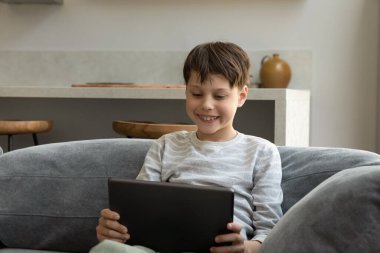 Dijital tablet kullanan mutlu genç çocuk.