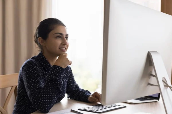 Heureuse dirigeante indienne d'entreprise qui travaille sur un moniteur de bureau — Photo