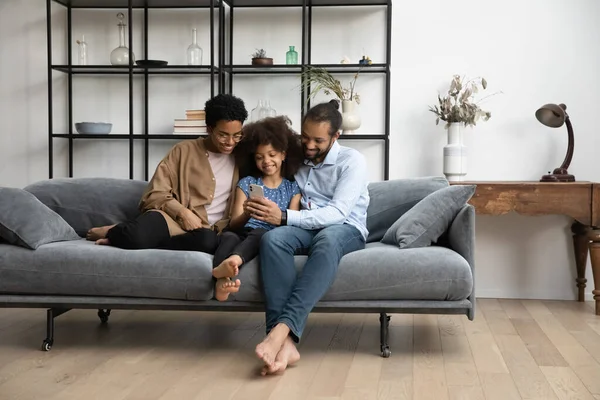 Família afro-americana feliz usando celular em casa. — Fotografia de Stock