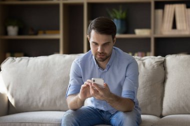 Odaklanmış milenyum çocuğu koltukta cep telefonu kullanıyor.