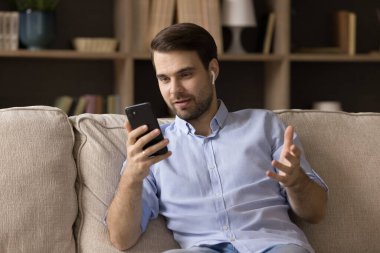 Kablosuz kulaklık kullanan pozitif nişanlı genç iş adamı