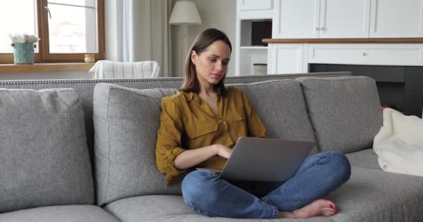 Nachdenkliche junge Frau tippt zu Hause auf Laptop — Stockvideo