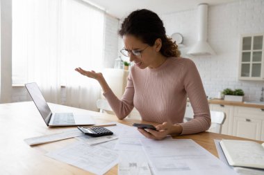 Gözlüklü kafası karışık bir kadın fatura hesaplıyor, para sıkıntısı çekiyor.