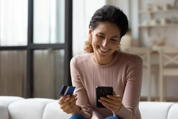 Blisko uśmiechnięta kobieta płaci kartą kredytową, za pomocą smartfona — Zdjęcie stockowe