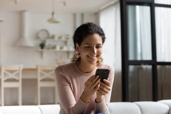 Närbild leende kvinna som håller smartphone, sitter på soffan — Stockfoto