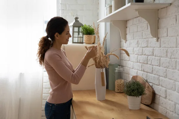 Lächelnde Frau dekoriert neue Wohnung, macht Strauß trockener Pflanzen — Stockfoto