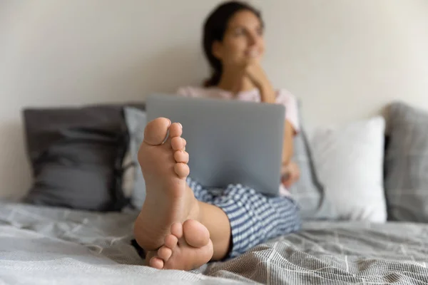 Close up feet of dreamy woman sitting relaxing on bed — Stock Photo, Image