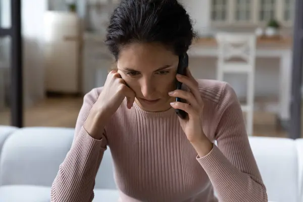 Крупним планом нещасна жінка розмовляє по телефону, чуючи погані новини — стокове фото