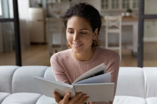 Großaufnahme lächelnde Frau liest Buch, sitzt auf gemütlicher Couch — Stockfoto