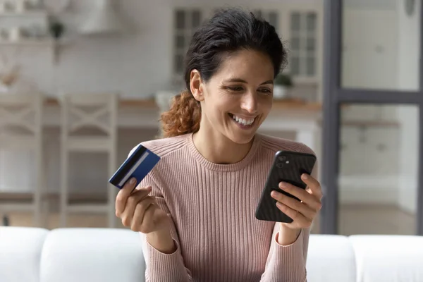 Blisko szczęśliwy kobieta trzyma kartę kredytową, za pomocą smartfona — Zdjęcie stockowe