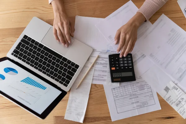 Top vue femme comptable compter les impôts, à l'aide d'un ordinateur portable et calculatrice — Photo