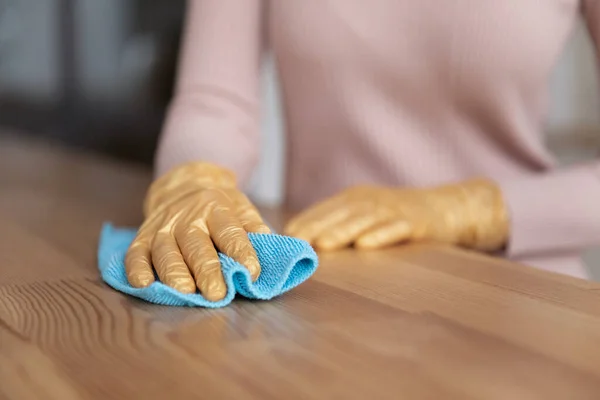 Закрыть обрезанные женщины в перчатках чистят деревянный стол — стоковое фото