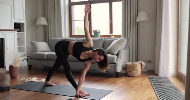 Mince jeune femme étirant les muscles debout dans une posture de yoga triangle — Video