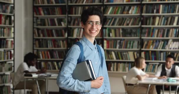 Guy student med ryggsäck innehar läroböcker pose i universitetsbiblioteket — Stockvideo
