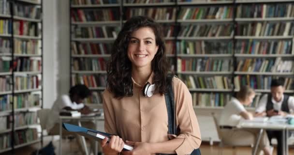 Retrato de una atractiva estudiante posando de pie en la biblioteca del campus — Vídeo de stock