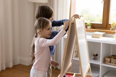 Oyuncak küçük beyaz tahtaya resim çizen iki sevimli kardeş çocuk.