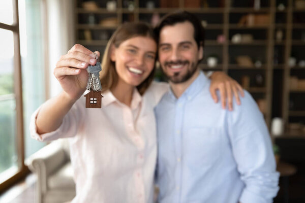 Happy young family couple of tenants receiving, holding keys
