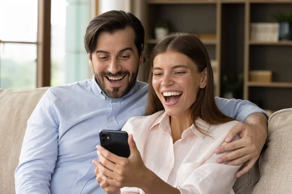 Ευτυχισμένο ενθουσιασμένο νεαρό ζευγάρι κοιτάζοντας την οθόνη smartphone — Φωτογραφία Αρχείου