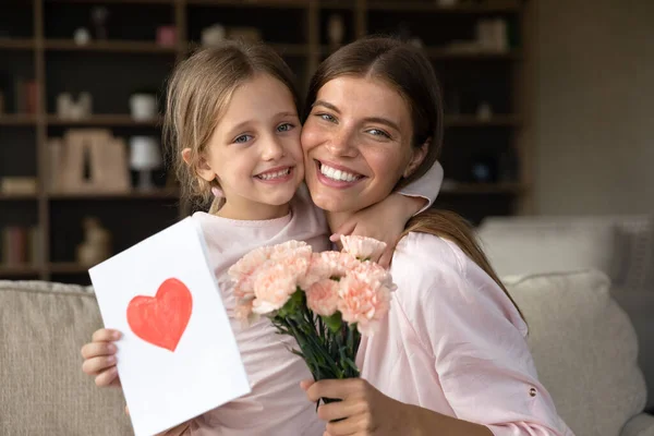 Wdzięczna mama przytulanie córka dziewczyna trzymając kwiaty bukiet — Zdjęcie stockowe