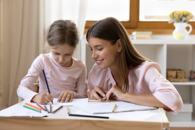 Odaklanmış küçük kızı izleyen mutlu anaokulu öğretmeni.