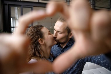 Birbirine aşık mutlu bir çift, el ve kalp şeklinde bir çerçeve.