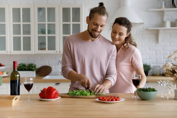 Happy millennial husband cooking romantic dinner, talking to beautiful wife — Stock Photo, Image