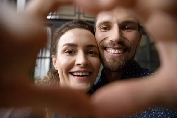 Ευτυχισμένο χαρούμενο ζευγάρι χρονολόγηση πορτρέτο μέσα από το σχήμα καρδιάς χέρι πλαίσιο — Φωτογραφία Αρχείου