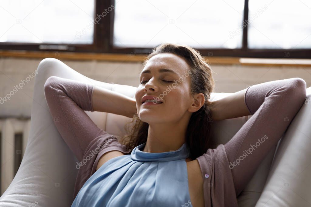 Happy beautiful woman resting in comfortable armchair with closed eyes