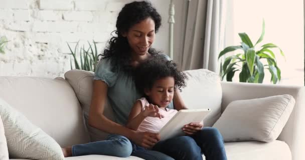 Donna africana sua figlia rilassarsi sul divano utilizzando tablet digitale — Video Stock