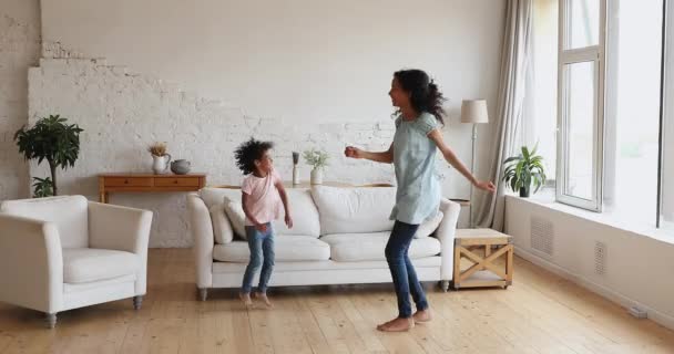 Mamá africana e hija pequeña escuchan música bailando en casa — Vídeos de Stock
