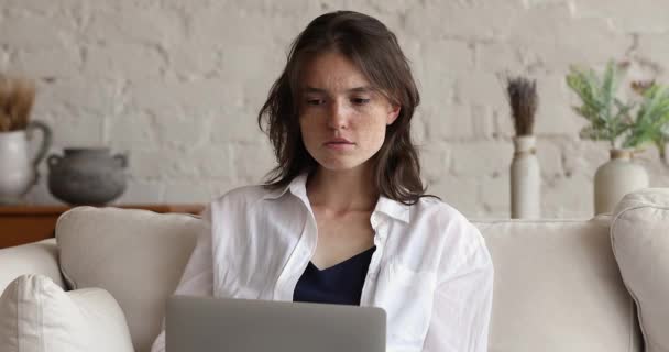 Frau blickt auf Laptop-Bildschirm und freut sich über gute Nachrichten — Stockvideo