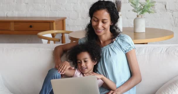 Afrikanska mamma och dotter använder laptop koppla av på soffan — Stockvideo