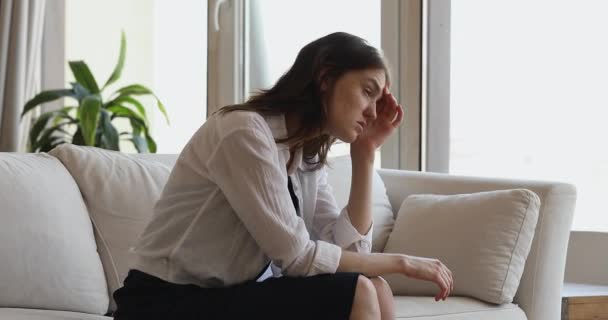 Mulher senta-se no sofá pensa sobre relacionamentos se sente infeliz — Vídeo de Stock