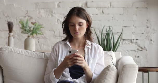 Młoda kobieta trzyma smartfon czytać złe wiadomości czuje się zaniepokojony — Wideo stockowe
