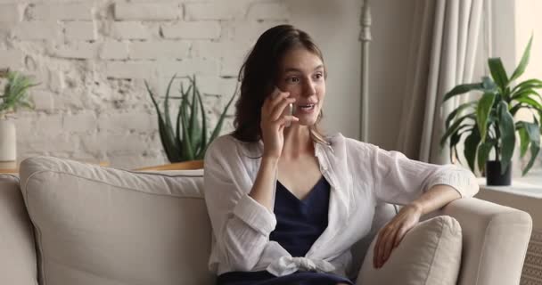 Hübsche Frau sitzt auf Sofa und genießt schöne Gespräche auf dem Handy — Stockvideo