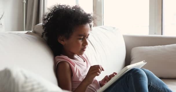 Αφρικανική κοπέλα κάθεται στον καναπέ στο σπίτι χρήση ψηφιακή δισκίο — Αρχείο Βίντεο
