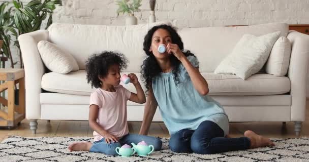 Африканка, її дочка тримає вдома іграшкові чашки. — стокове відео