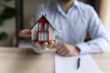 Emlakçı elinde küçük bir ev düzeni tutuyor. Yakın plan.