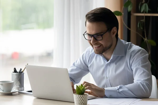 Uomo d'affari si siede alla scrivania guardando lo schermo del computer portatile si sente soddisfatto — Foto Stock