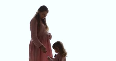 Sevimli küçük kız hamile anne beyaz arka planda oynuyor.