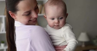 Bebek anne kollarında oturur. İlgiyle etrafına bak.