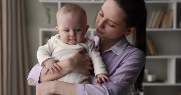 Vårdande mamma håller barnet på händerna talar lek med barnet — Stockvideo