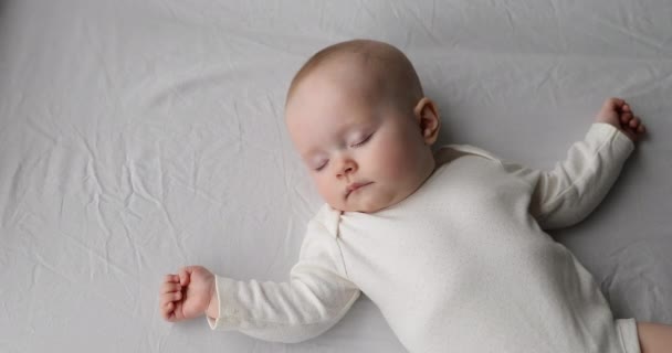 Un bébé en bonne santé dort seul sur un grand lit écartant les mains — Video