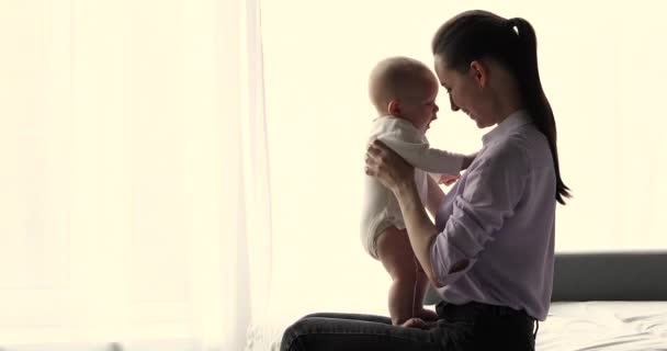 Mãe feliz sentar na cama brincando com bebê engraçado bonito — Vídeo de Stock