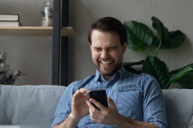 Adam kanepeye oturur, akıllı telefon şakaları yapar, komik videolarda güler.