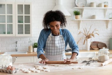 Afrikalı ev hanımı önlük takıyor merdane mangırı düzleştiriyor