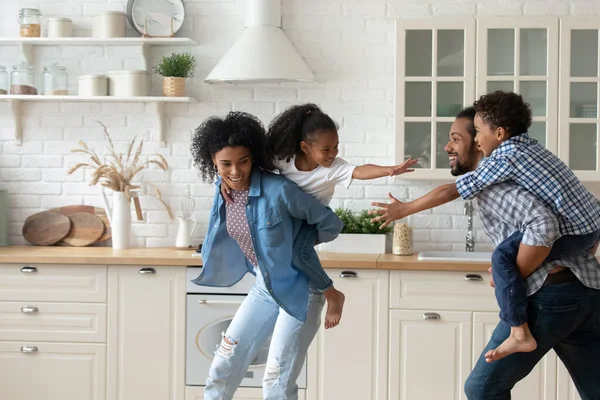 African parents ride on backs children play together at home — Stock Photo, Image